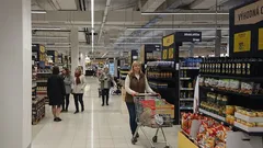 Nakupování v supermarketu, lidé s vozíky mezi regály s potravinami.